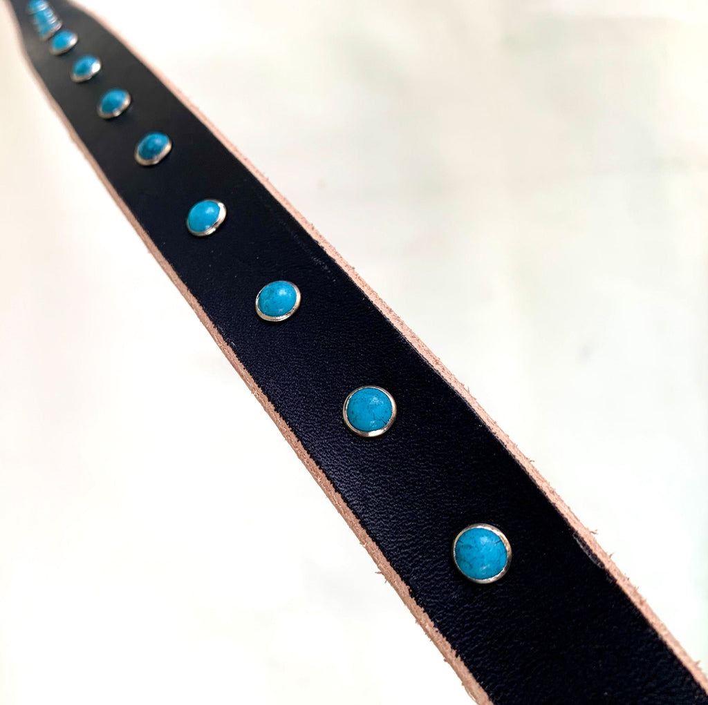 A black leather dog collar decorated with round turquoise blue stone studs.